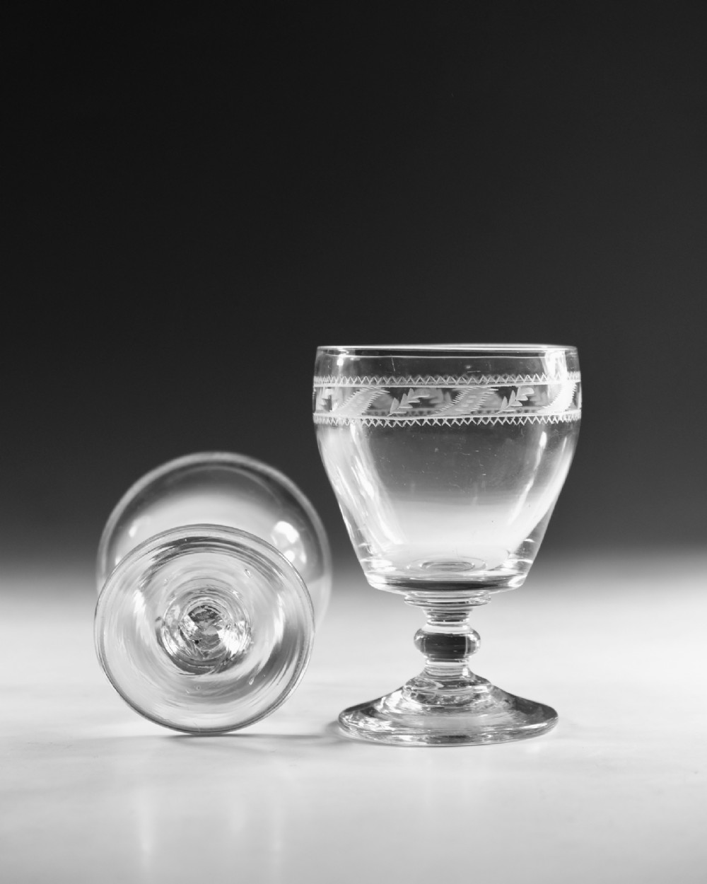 A pair of clear Georgian glass rummers with hand-engraved geometric borders and knopped stems on circular bases. View VII
