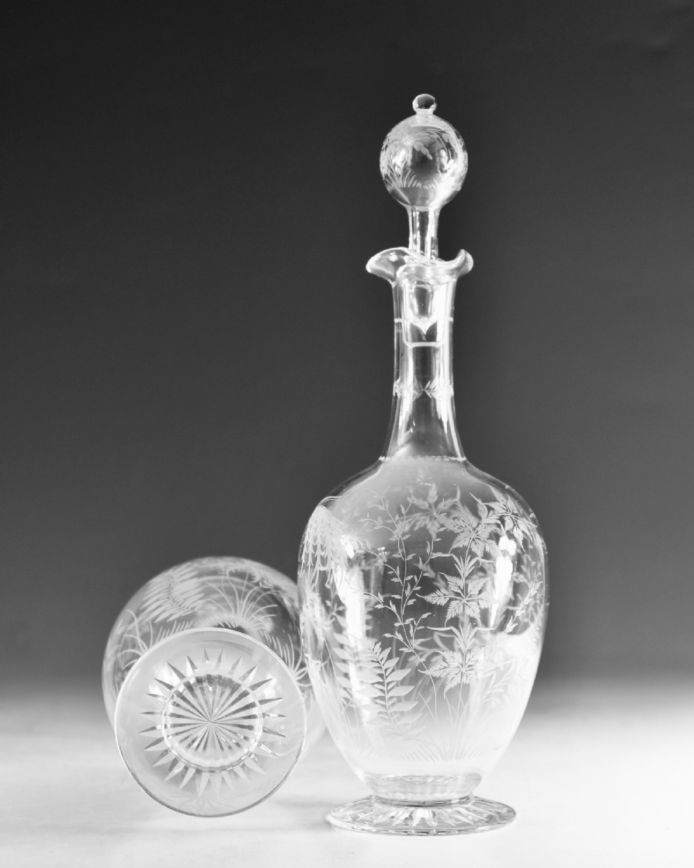 A pair of clear Victorian glass decanters featuring etched botanical fern decoration, narrow necks, ruffled collars, and spherical stoppers. View VII