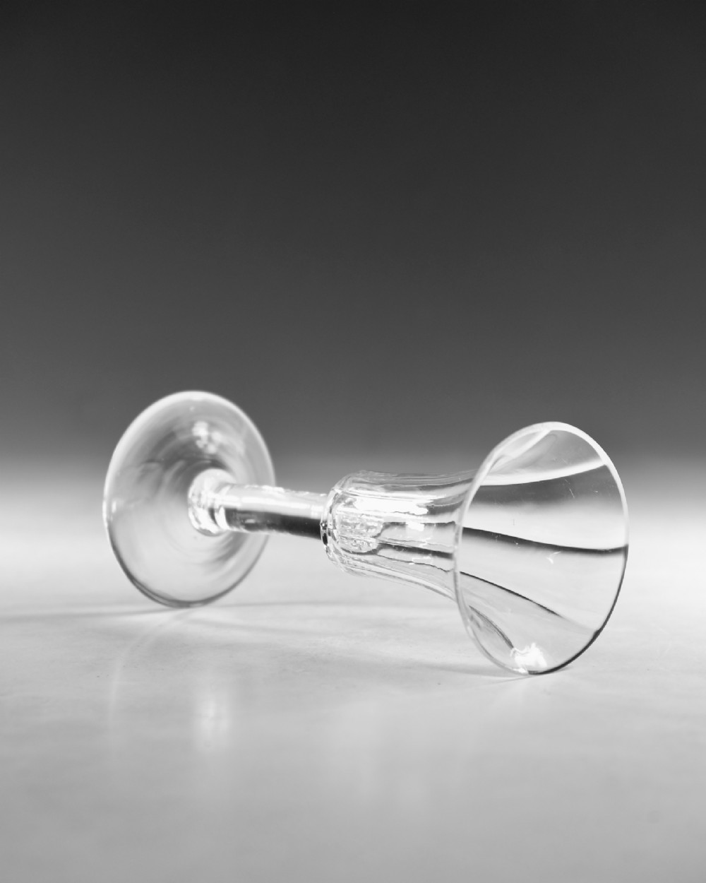 An eighteenth-century clear lead glass ale flute featuring a ribbed trumpet-shaped bowl on a straight stem with a conical base. View IV