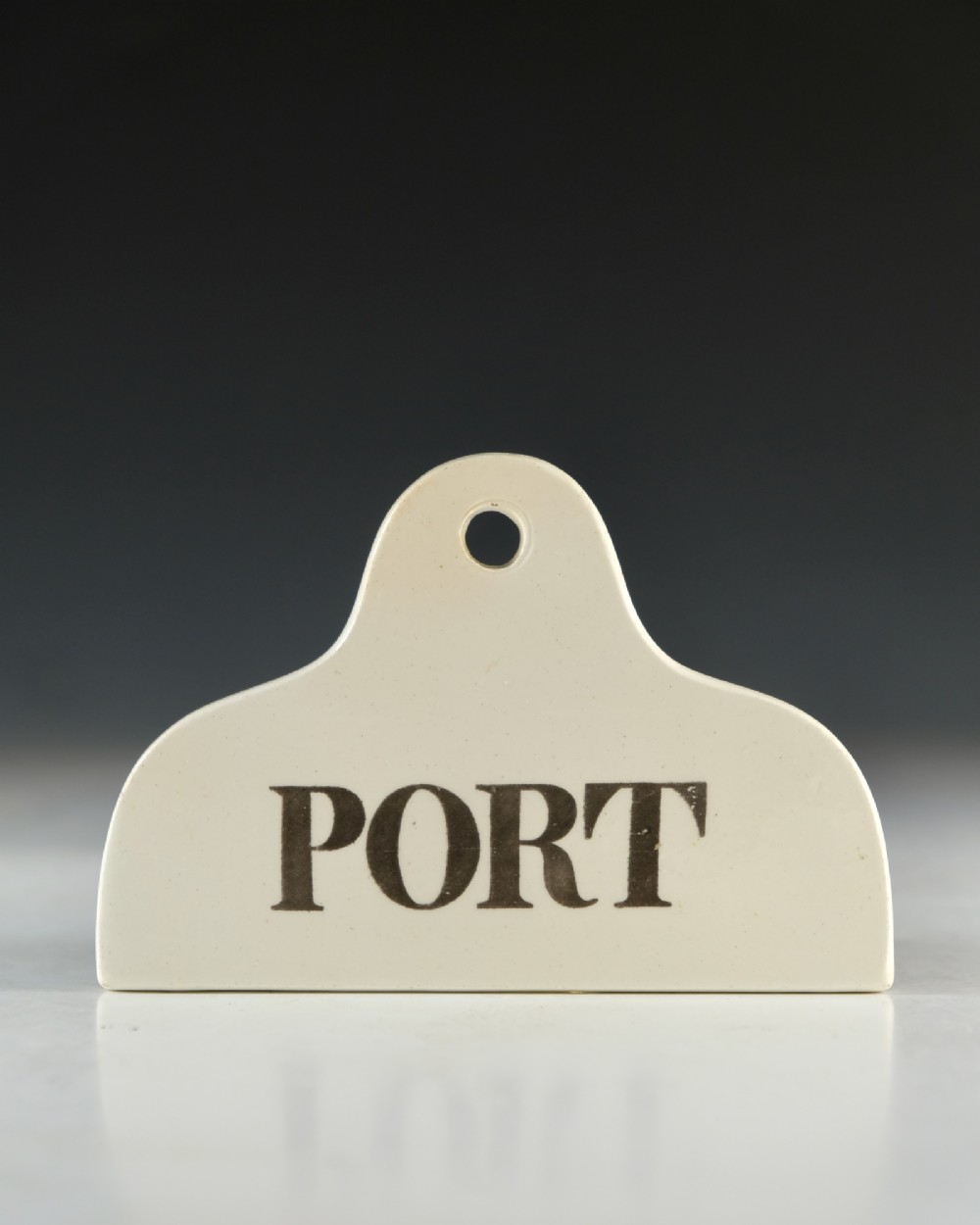 A mid-19th century creamware ceramic bin label with a top hole and the word PORT printed in bold black lettering. View II