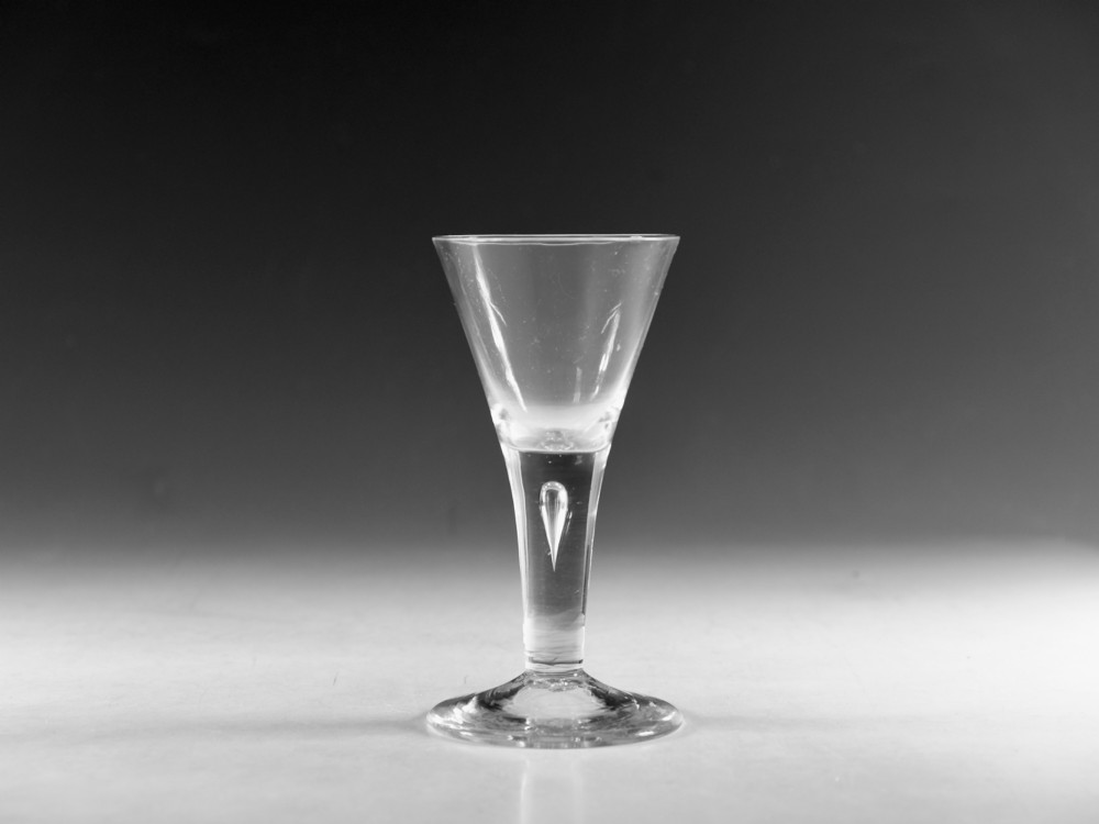 An eighteenth-century clear glass wine vessel featuring a conical bowl, a plain stem enclosing an elongated air tear, and a circular conical foot.