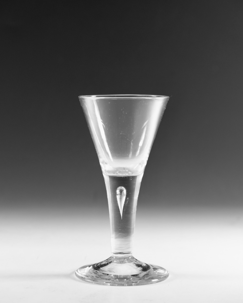 An eighteenth-century clear glass wine vessel featuring a conical bowl, a plain stem enclosing an elongated air tear, and a circular conical foot. View II