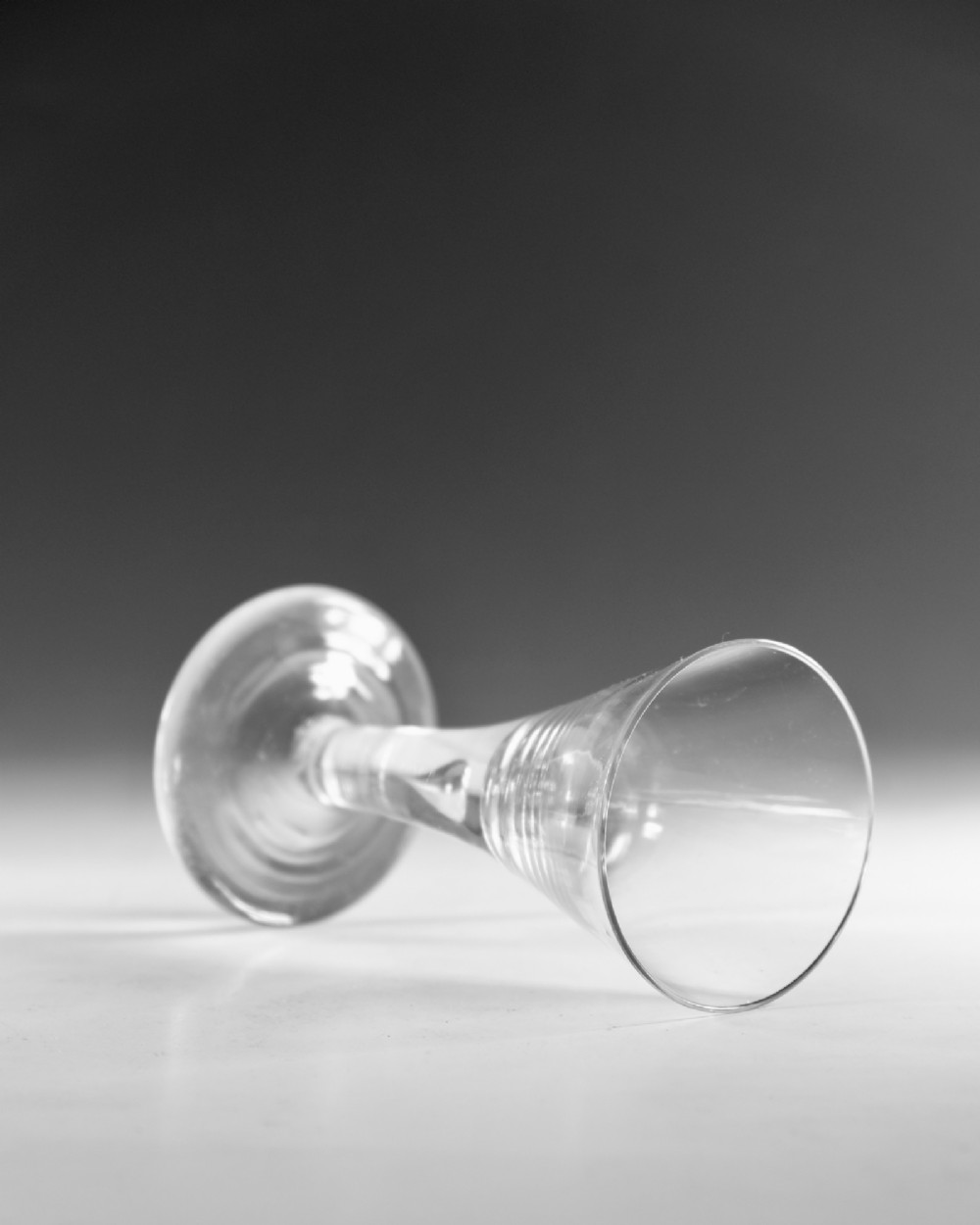 An eighteenth-century clear glass wine vessel featuring a conical bowl, a plain stem enclosing an elongated air tear, and a circular conical foot. View IV