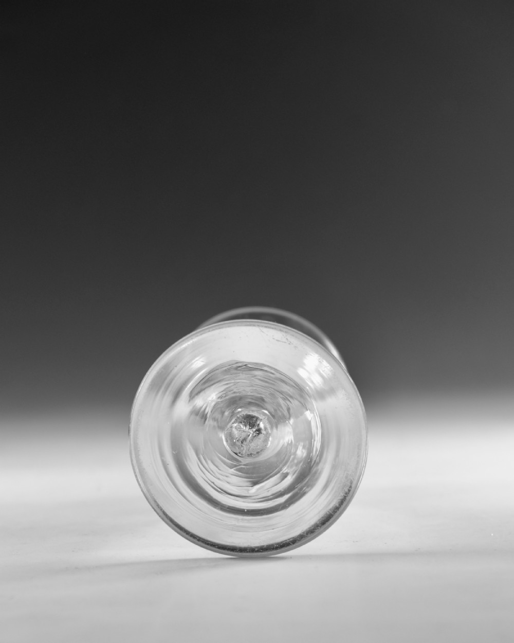 An eighteenth-century clear glass wine vessel featuring a conical bowl, a plain stem enclosing an elongated air tear, and a circular conical foot. View V