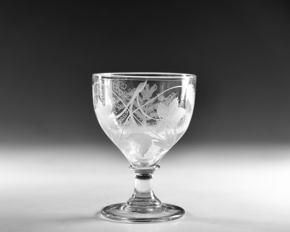 A clear glass Georgian rummer goblet featuring wheel-engraved botanical fern and bird motifs above a short knopped stem and circular base. View II