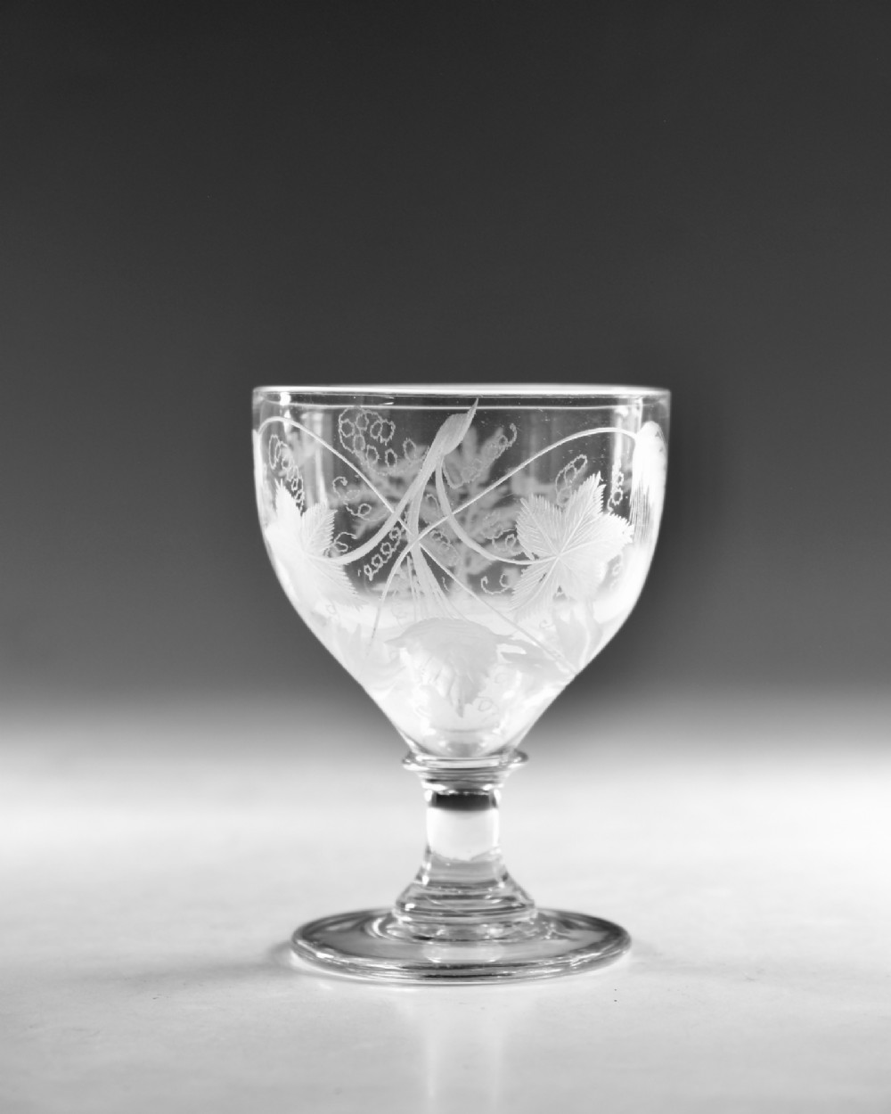 A clear glass Georgian rummer goblet featuring wheel-engraved botanical fern and bird motifs above a short knopped stem and circular base. View III