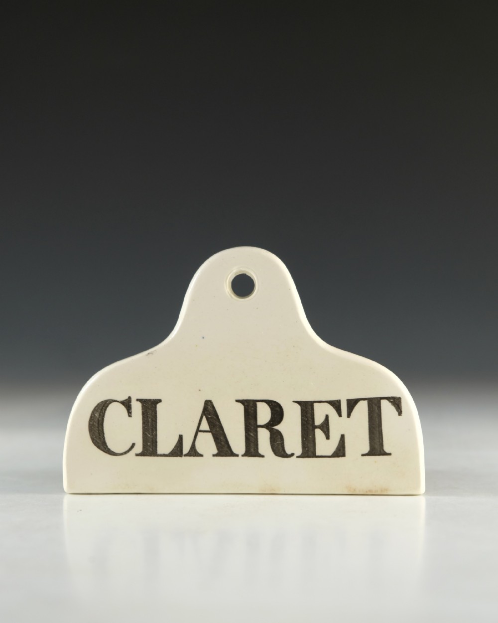 A mid 19th-century cream ceramic wine bin label stamped with the word CLARET in black serif lettering. View II