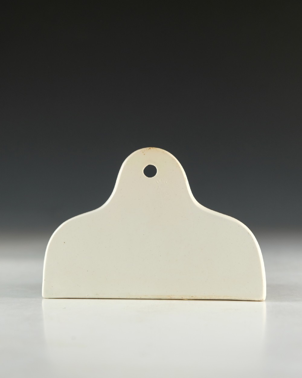 A mid-19th-century cream ceramic brandy bin label featuring black serif lettering and an arched crest with a central hanging hole. View III