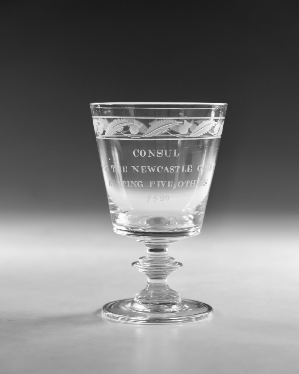 An antique clear glass Georgian rummer featuring wheel-engraved inscriptions and foliage motifs above a knopped stem. View II