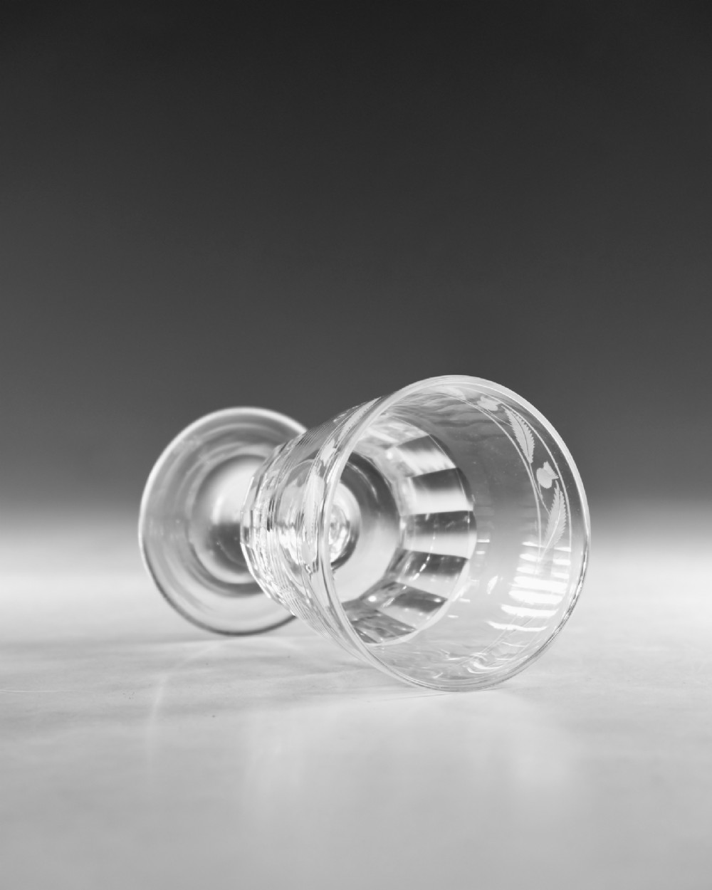A clear Georgian lead crystal rummer glass featuring an engraved inscription reading LEOPOLD above a facet-cut lower bowl and knopped stem. View V