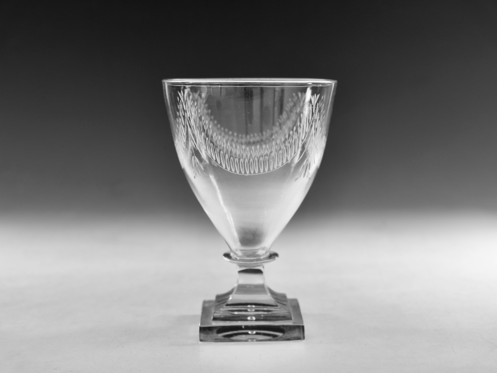 A Georgian clear glass rummer featuring an engraved festoon bowl on a square mould-pressed pedestal base.