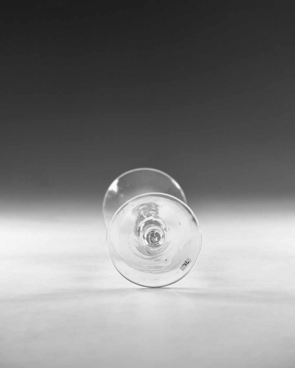 An 18th-century clear glass Georgian wine glass featuring a flared trumpet bowl, a knopped stem with an internal air teardrop inclusion, and a wide circular foot. View V