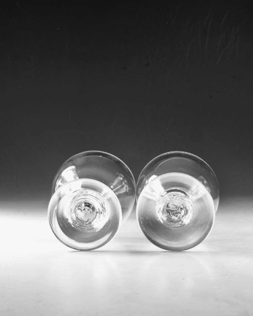 A set of four clear hand-blown Georgian glass rummers with wide funnel bowls, short collar stems, and circular flat bases. View VI