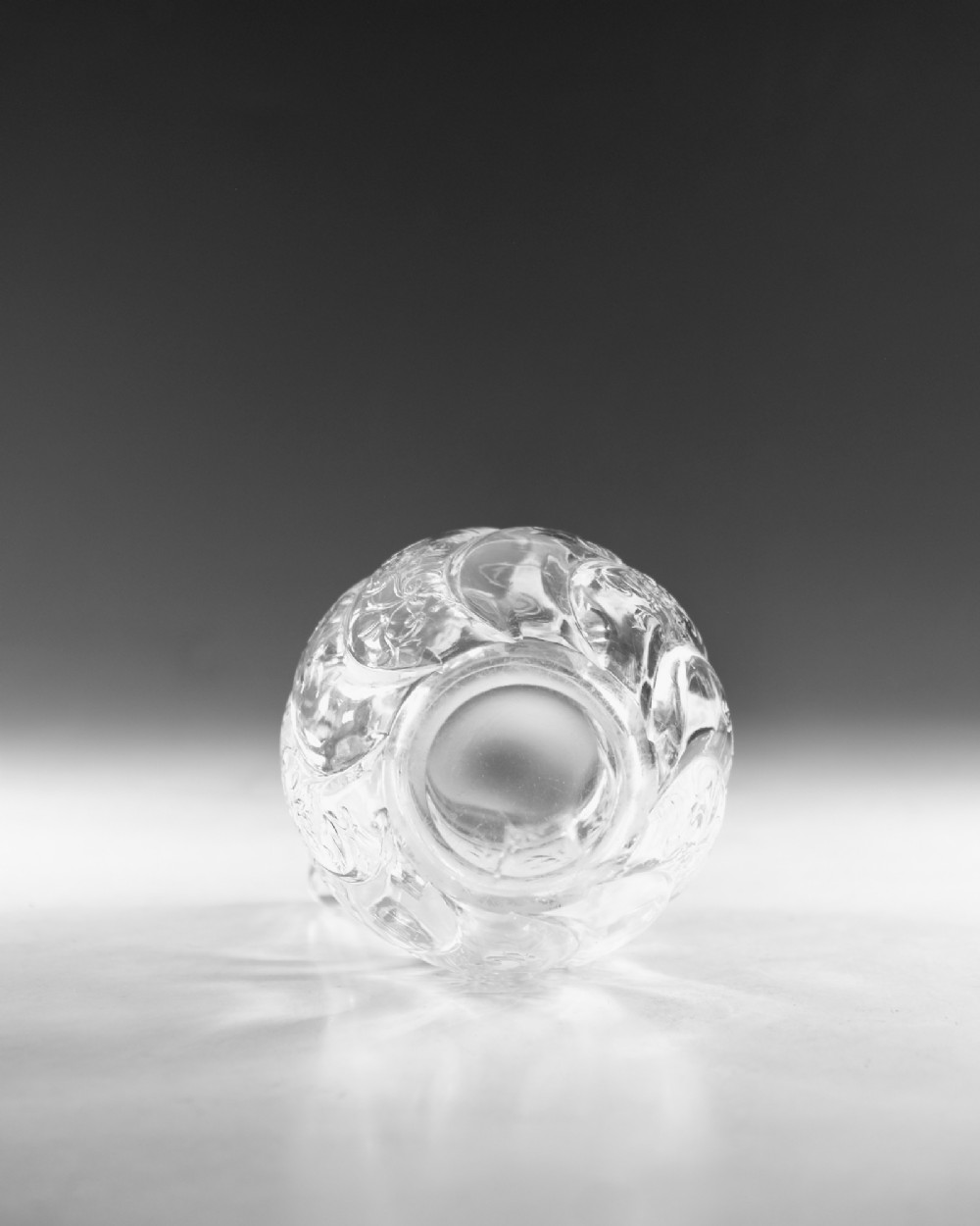 An antique clear glass jug featuring a bulbous swirl-moulded lower body with wheel-engraved floral motifs and a fitted handle. View VIII