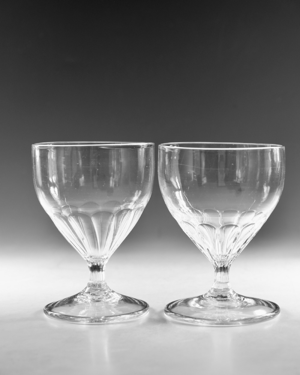 A pair of antique Georgian clear glass rummers featuring wide cylindrical bowls with fluted lower panels on short stems and circular bases. View III