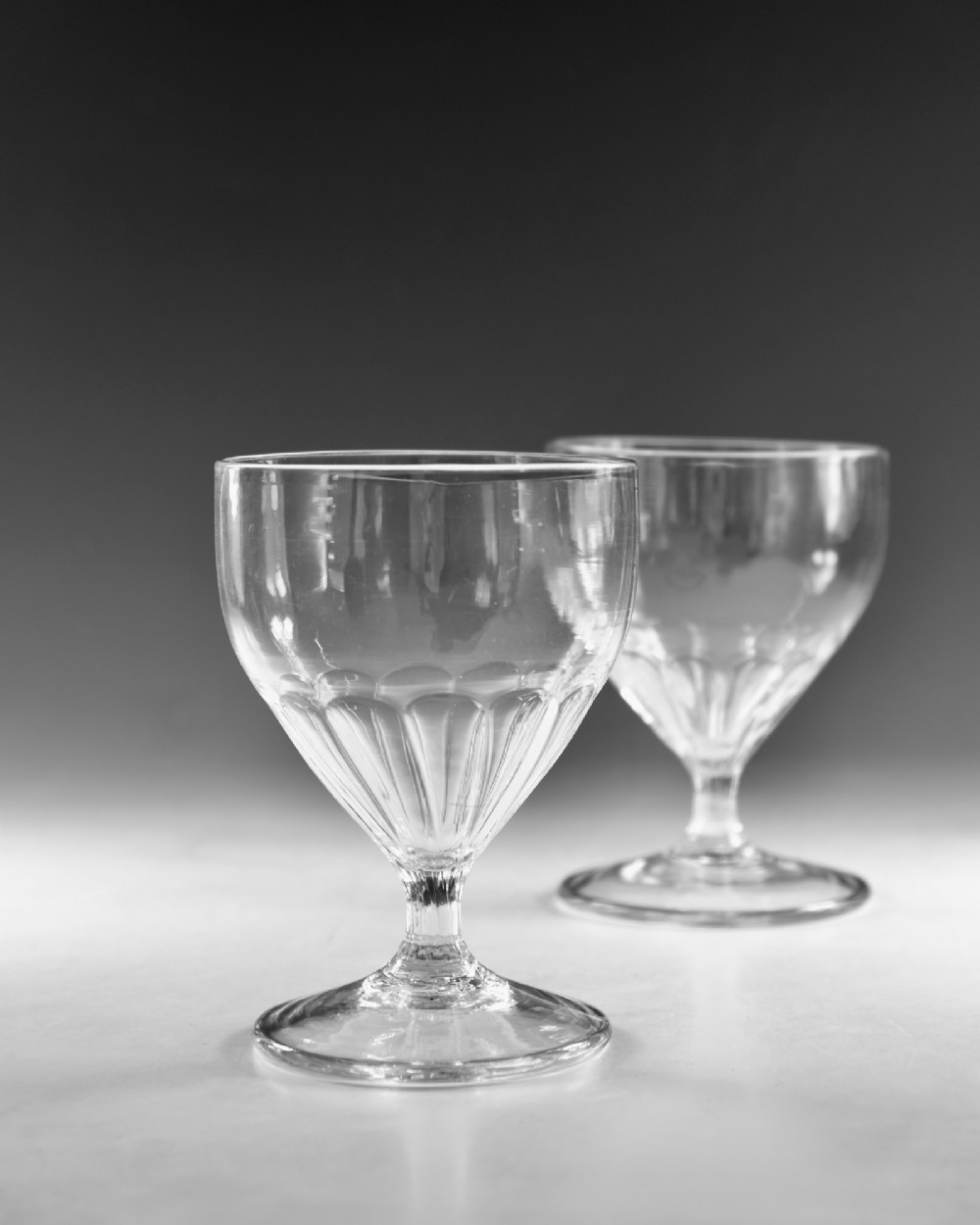 A pair of antique Georgian clear glass rummers featuring wide cylindrical bowls with fluted lower panels on short stems and circular bases. View IV