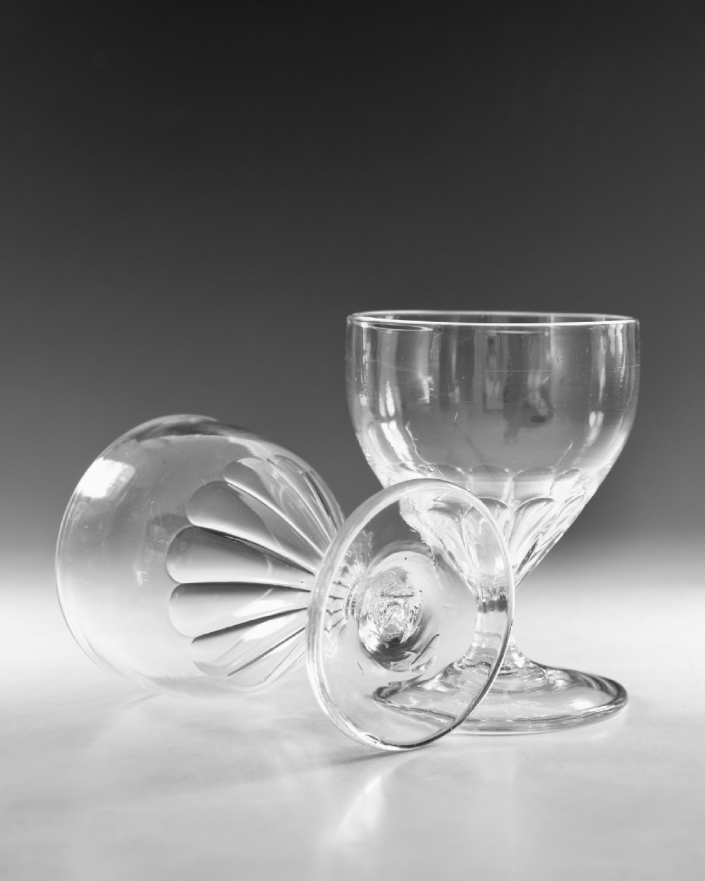 A pair of antique Georgian clear glass rummers featuring wide cylindrical bowls with fluted lower panels on short stems and circular bases. View VI
