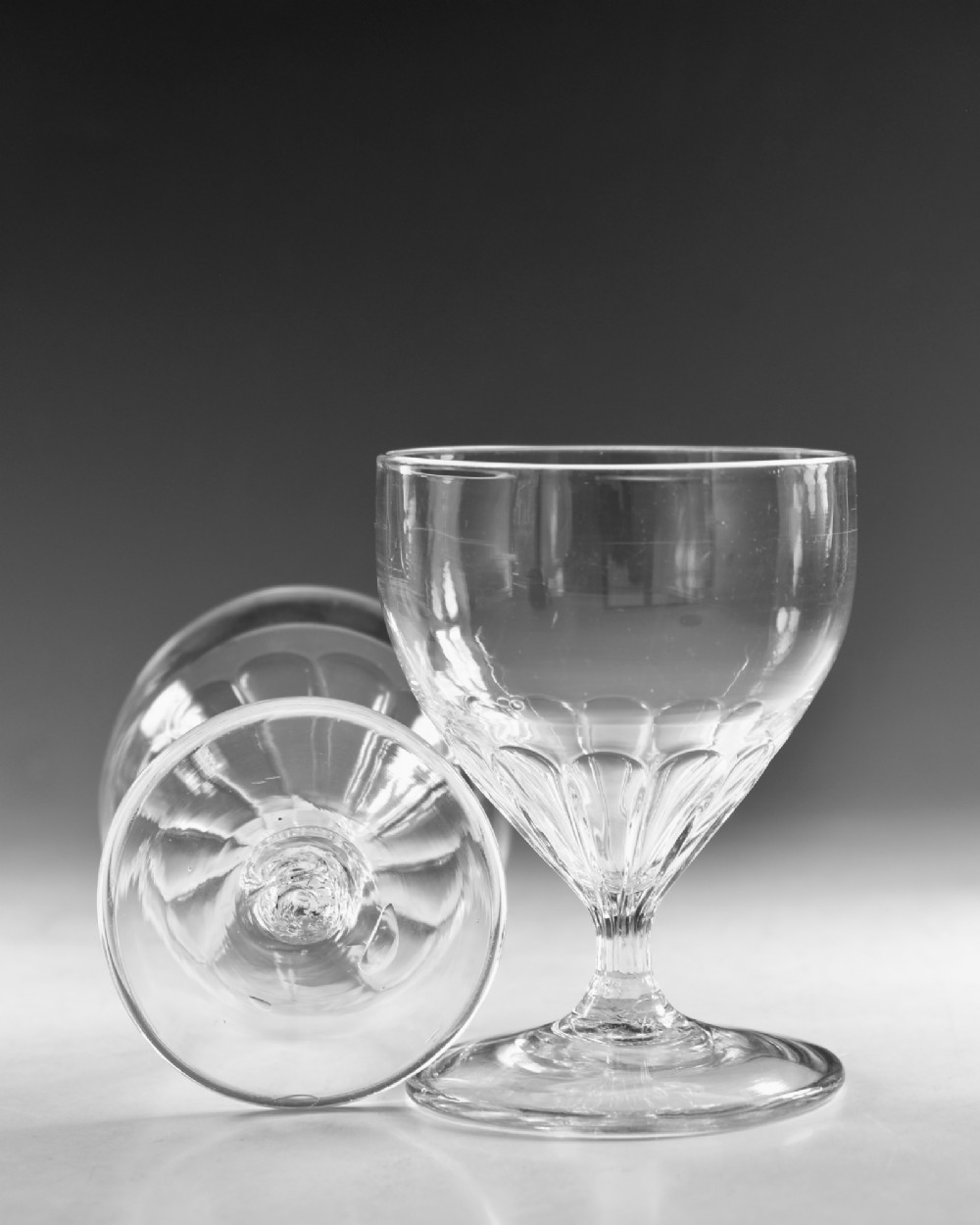 A pair of antique Georgian clear glass rummers featuring wide cylindrical bowls with fluted lower panels on short stems and circular bases. View VIII