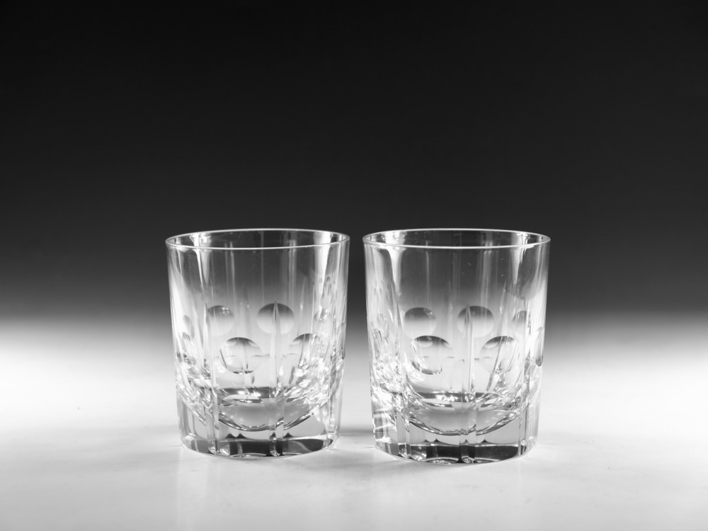 A pair of early twentieth-century clear cut glass tumblers featuring circular lens cuts and vertical fluting.