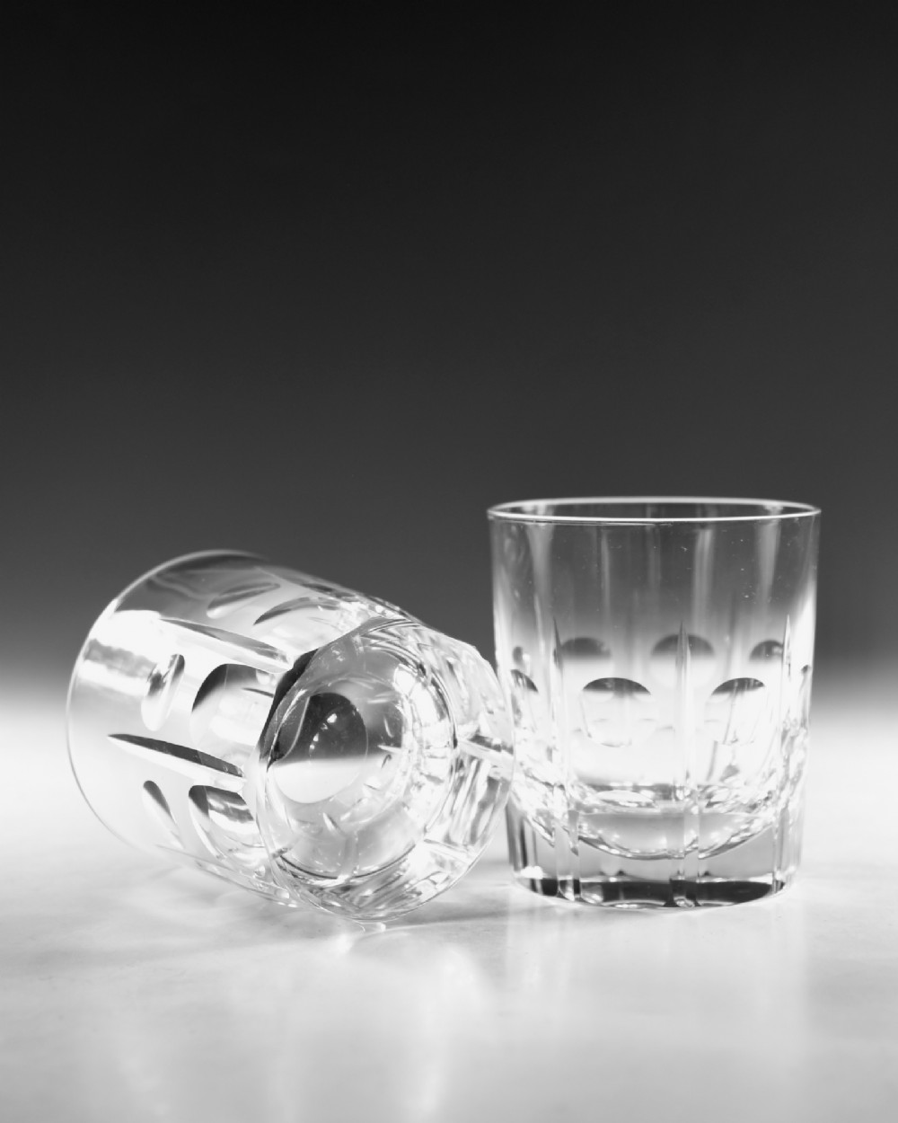 A pair of early twentieth-century clear cut glass tumblers featuring circular lens cuts and vertical fluting. View V