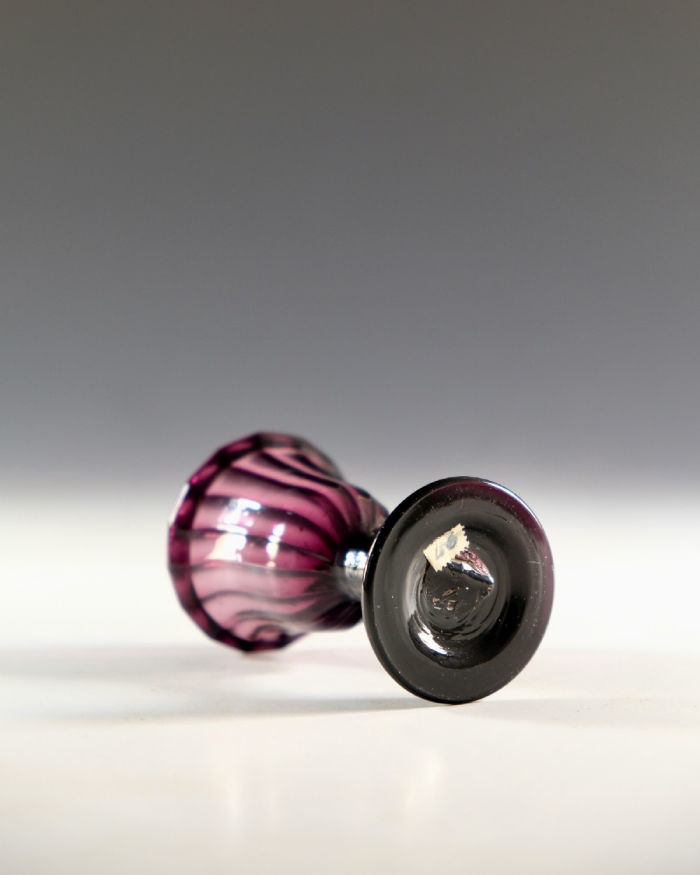 A Georgian amethyst purple glass egg cup with a fluted bowl, slender stem, and circular pedestal foot. View III