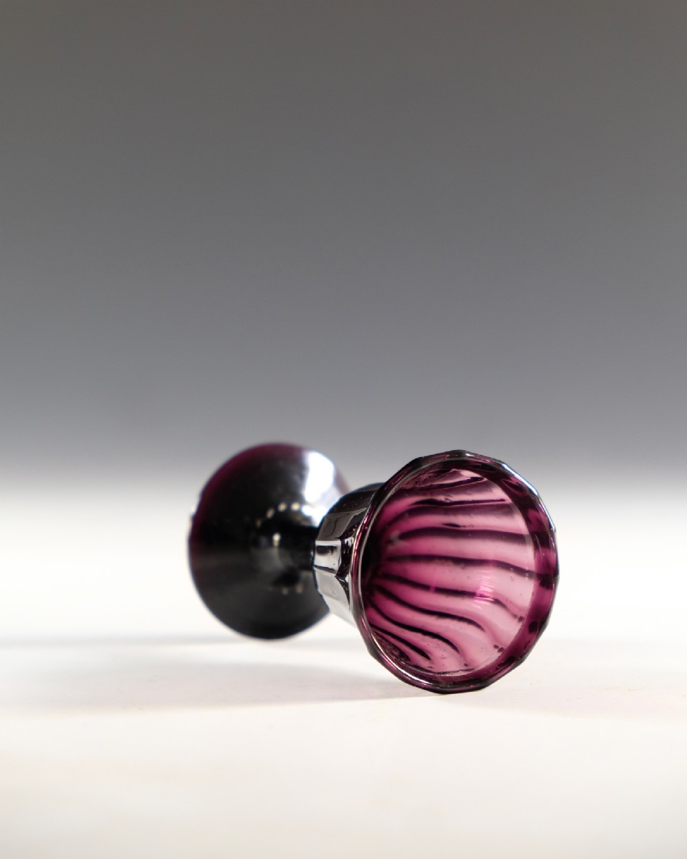 A Georgian amethyst purple glass egg cup with a fluted bowl, slender stem, and circular pedestal foot. View IV