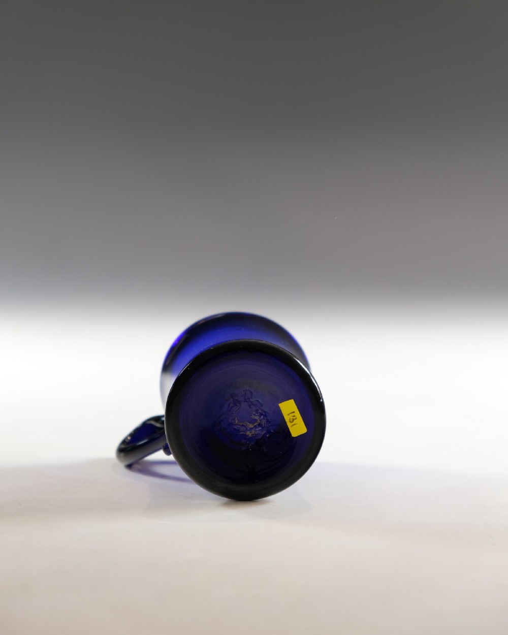 A small Georgian cobalt blue glass tankard with a curved applied handle and a flared base. View V