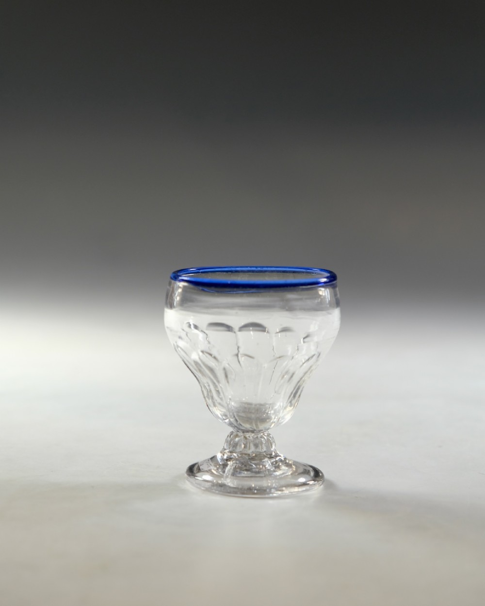 An 18th-century clear lead glass bonnet glass featuring a hand-applied cobalt blue rim, a honeycomb-moulded cup bowl, and a circular flat foot. View II