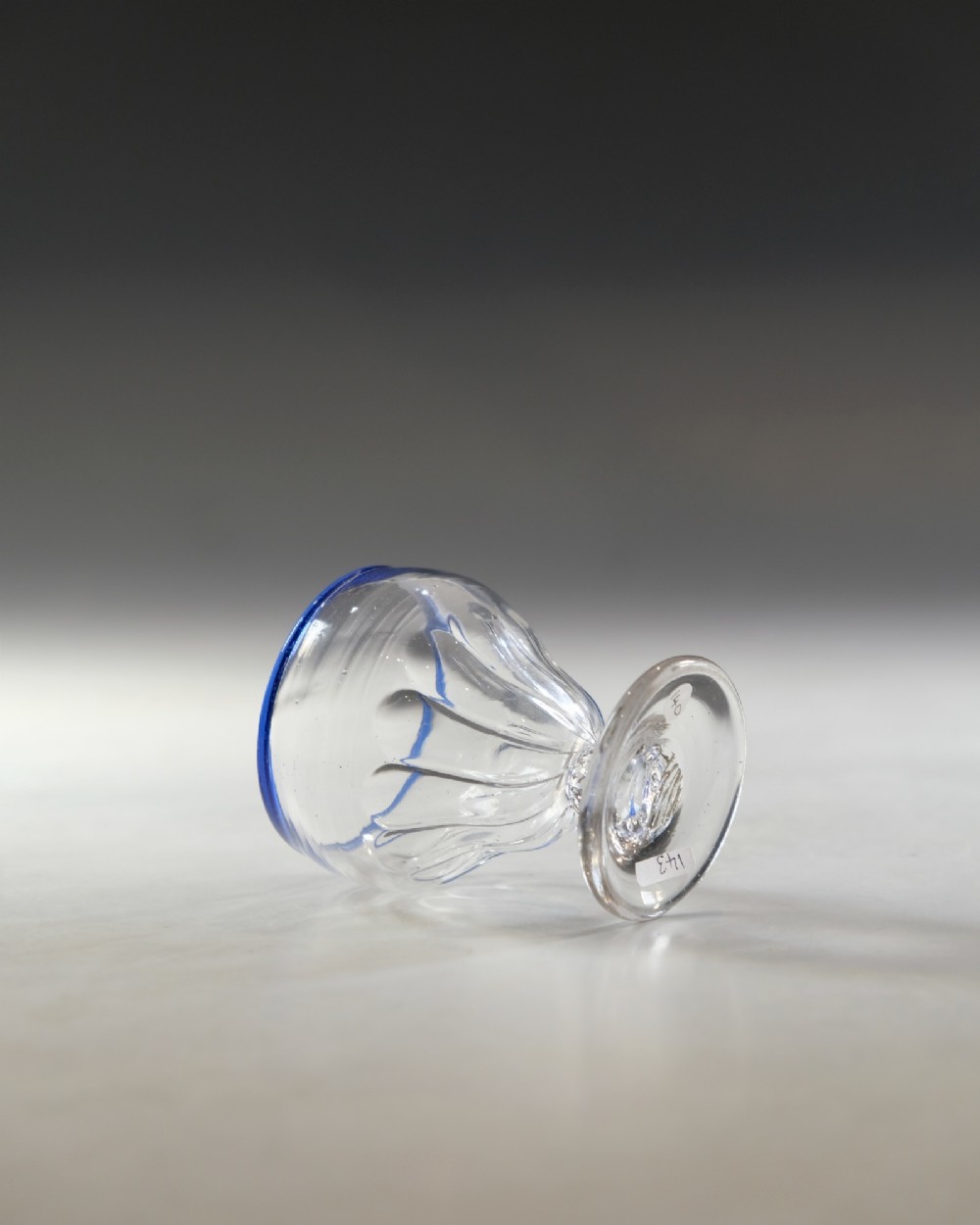 An 18th-century clear lead glass bonnet glass featuring a hand-applied cobalt blue rim, a honeycomb-moulded cup bowl, and a circular flat foot. View IV