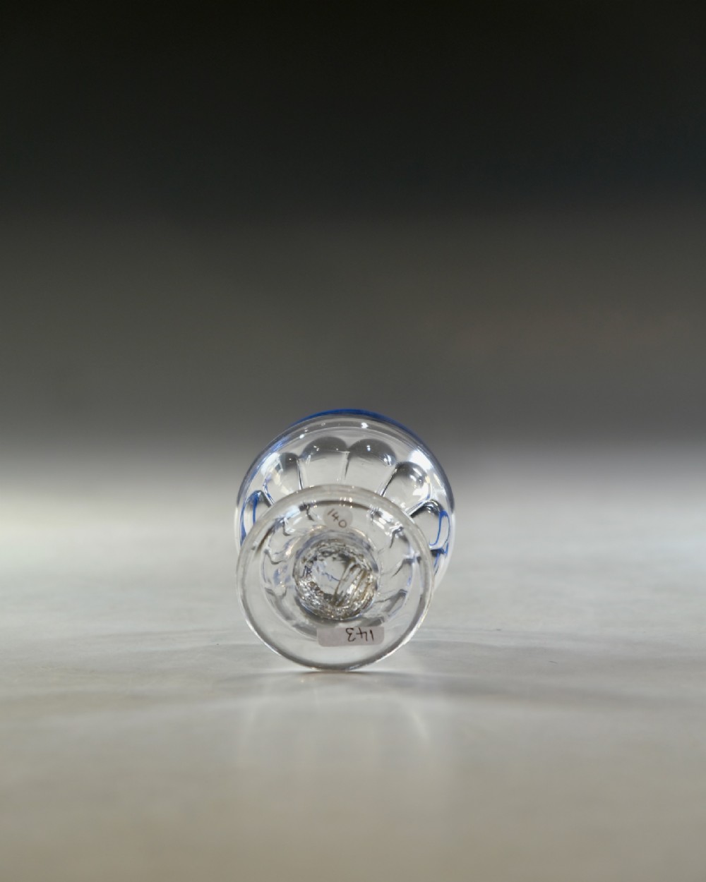 An 18th-century clear lead glass bonnet glass featuring a hand-applied cobalt blue rim, a honeycomb-moulded cup bowl, and a circular flat foot. View VI
