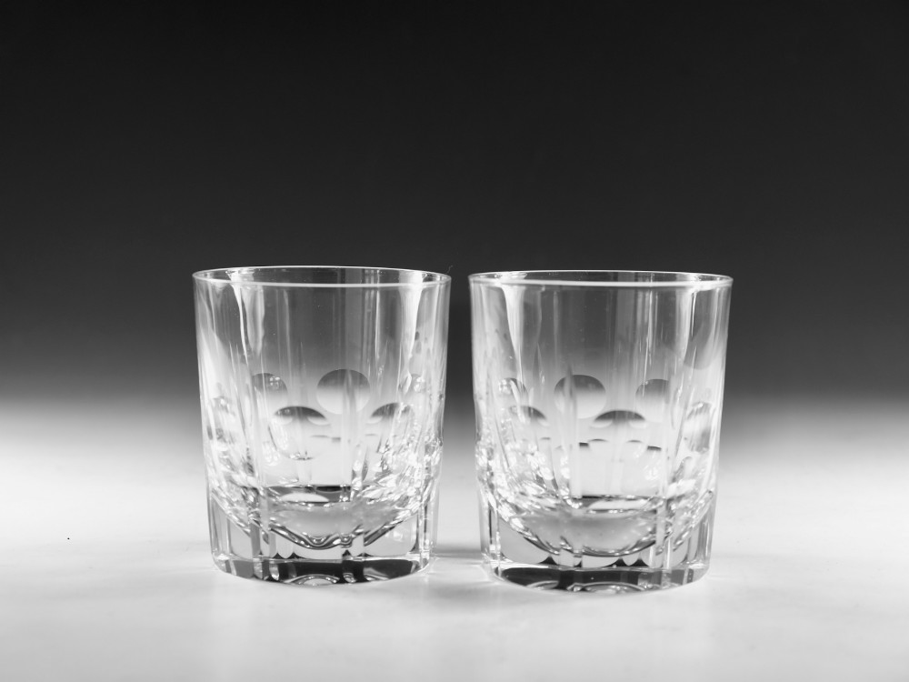A pair of clear cut-glass tumblers featuring circular printie cuts and vertical faceted lines around the lower body.