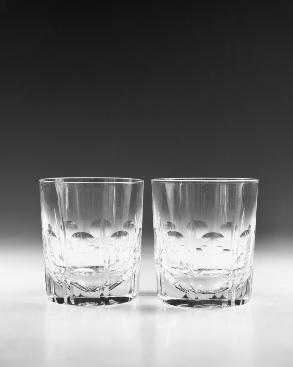 A pair of clear cut-glass tumblers featuring circular printie cuts and vertical faceted lines around the lower body. View II