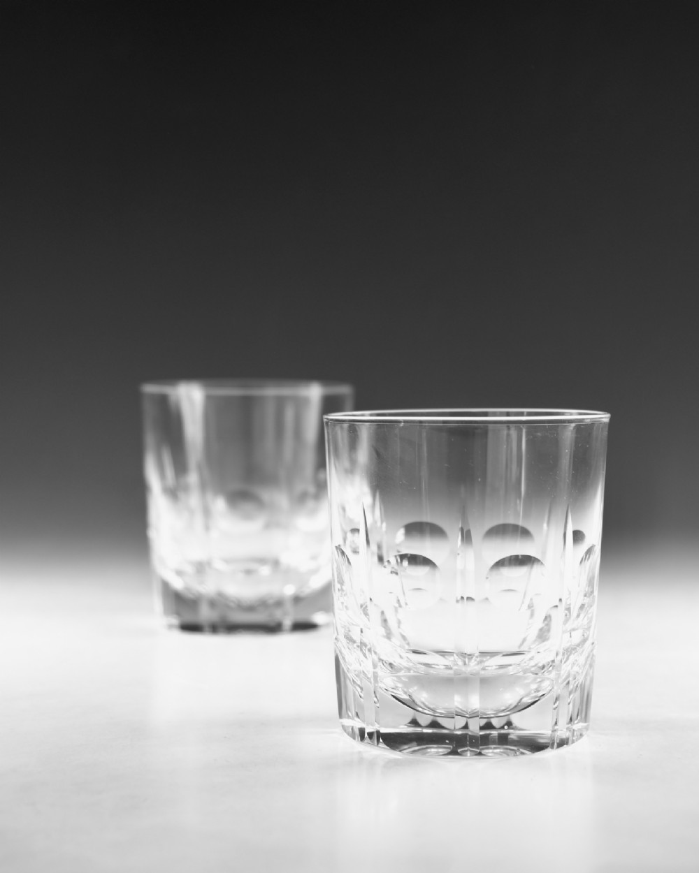 A pair of clear cut-glass tumblers featuring circular printie cuts and vertical faceted lines around the lower body. View IV