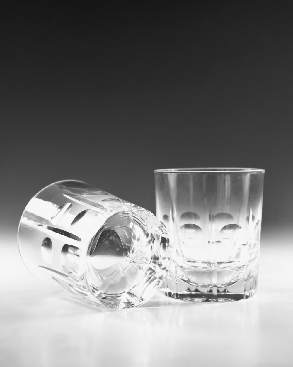 A pair of clear cut-glass tumblers featuring circular printie cuts and vertical faceted lines around the lower body. View V