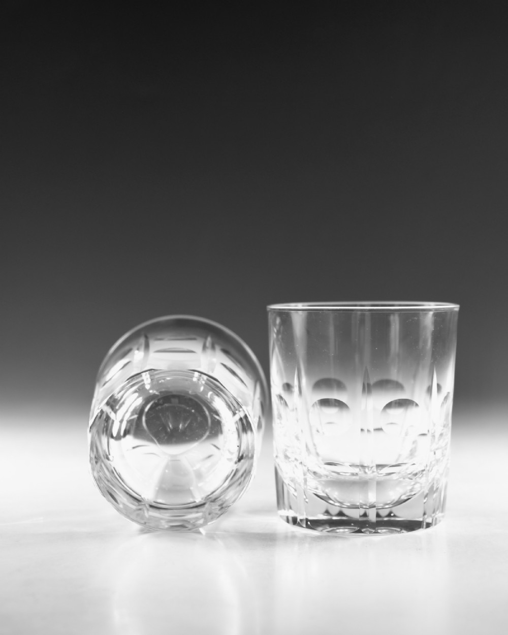 A pair of clear cut-glass tumblers featuring circular printie cuts and vertical faceted lines around the lower body. View VII