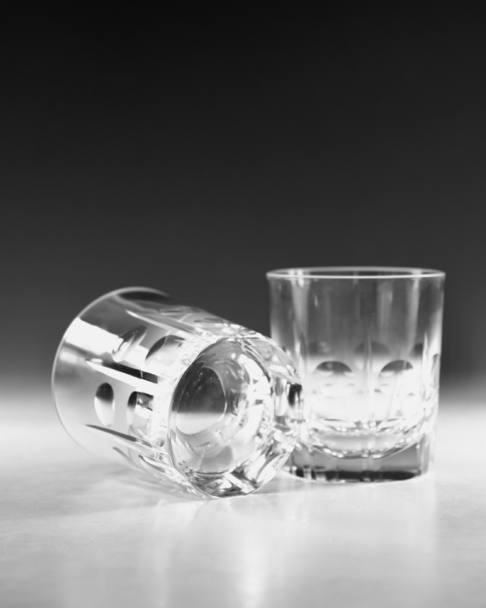 A pair of early 20th-century clear cut crystal tumblers featuring circular lens cuts and vertical faceted detail around the lower half. View V