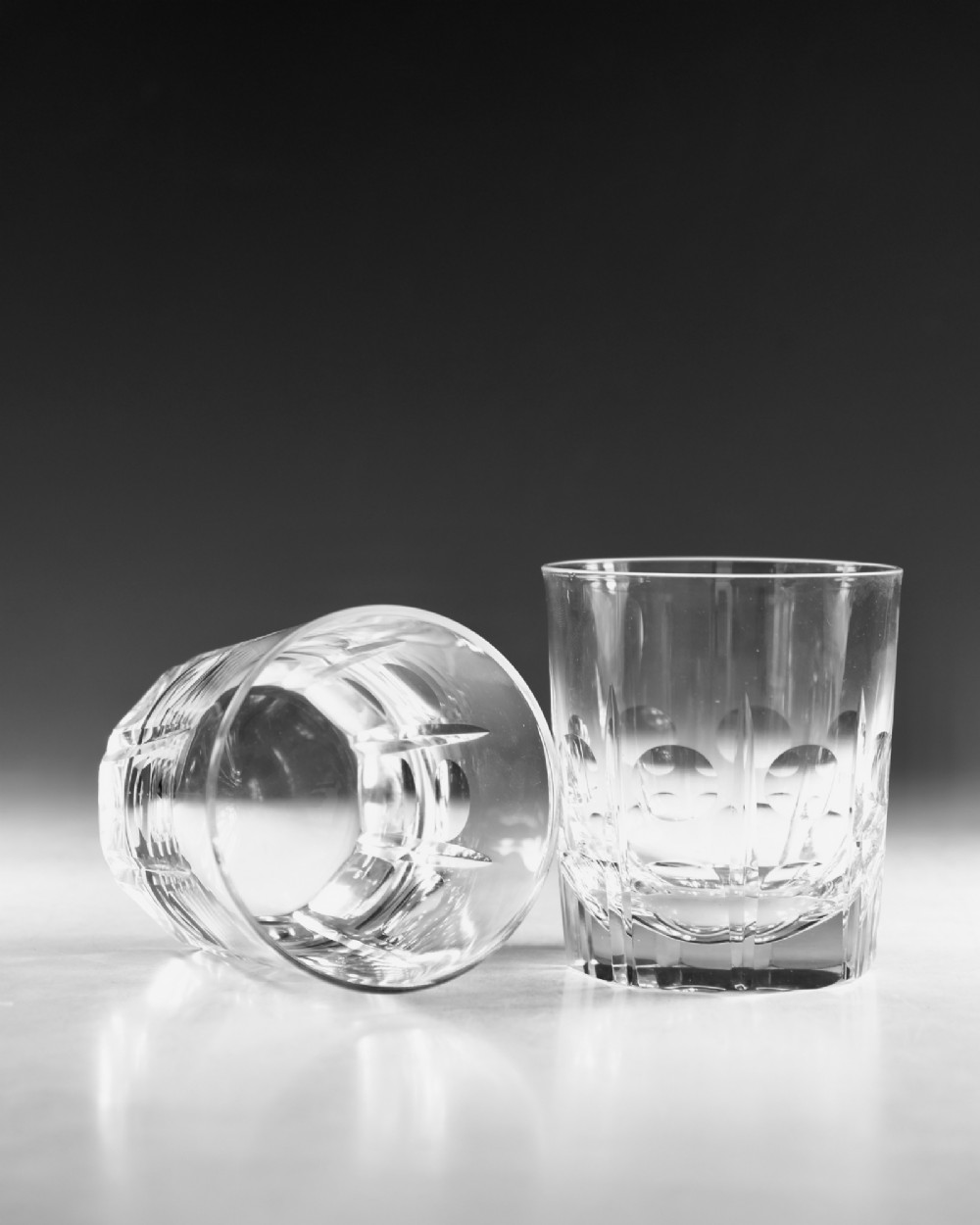 A pair of early 20th-century clear cut crystal tumblers featuring circular lens cuts and vertical faceted detail around the lower half. View VI