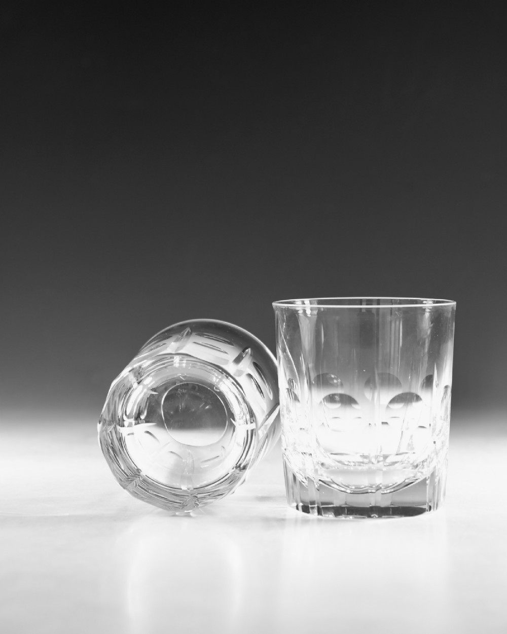 A pair of early 20th-century clear cut crystal tumblers featuring circular lens cuts and vertical faceted detail around the lower half. View VII
