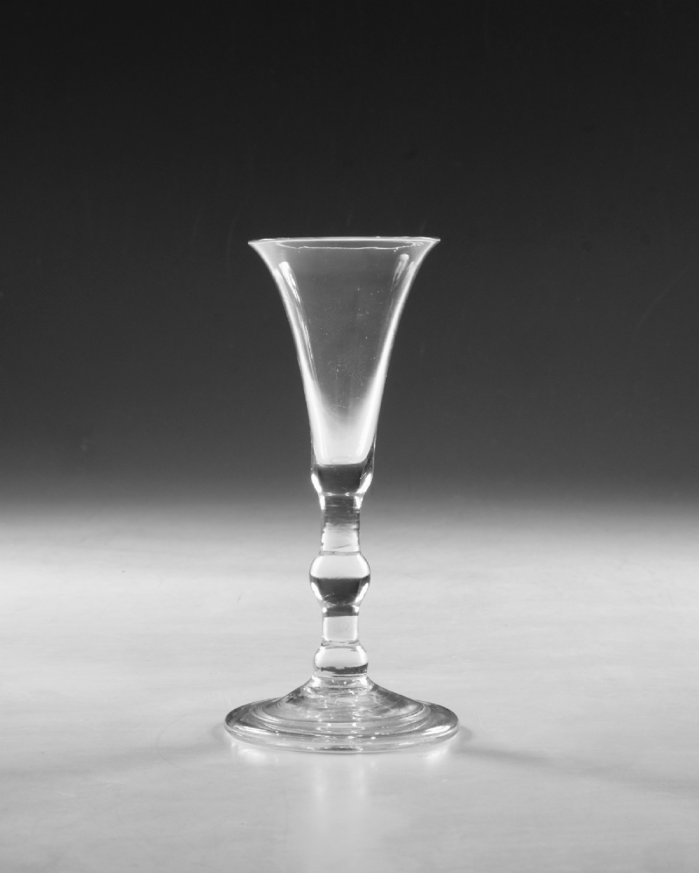 A clear Georgian lead glass vessel featuring a flared trumpet bowl, a central knapped stem, and a circular conical foot. View II