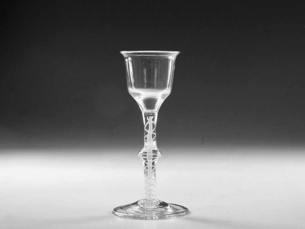 A Georgian clear lead glass wine glass featuring a bell-shaped bowl and a knopped stem with an internal white opaque twist pattern on a conical foot.
