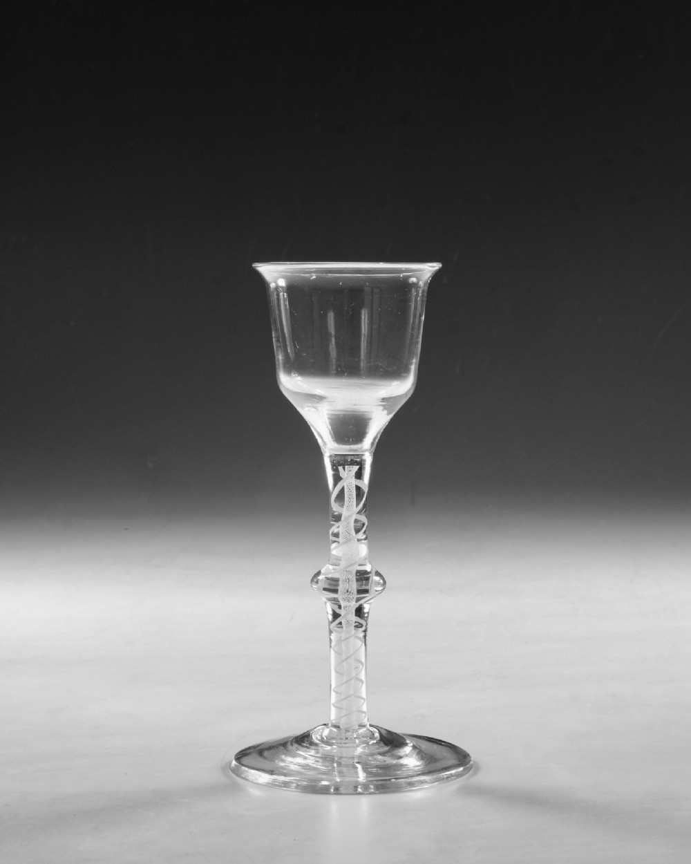 A Georgian clear lead glass wine glass featuring a bell-shaped bowl and a knopped stem with an internal white opaque twist pattern on a conical foot. View III