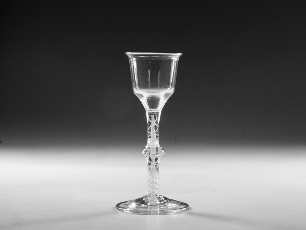 A Georgian clear lead glass wine glass featuring a bell-shaped bowl and a knopped stem with an internal white opaque twist pattern on a conical foot. View VII