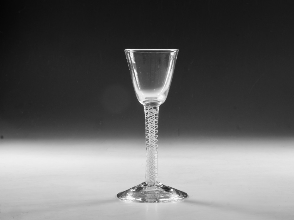 A Georgian clear lead crystal wine glass featuring a bell-shaped bowl, a stem with an internal white opaque twist pattern, and a conical foot.