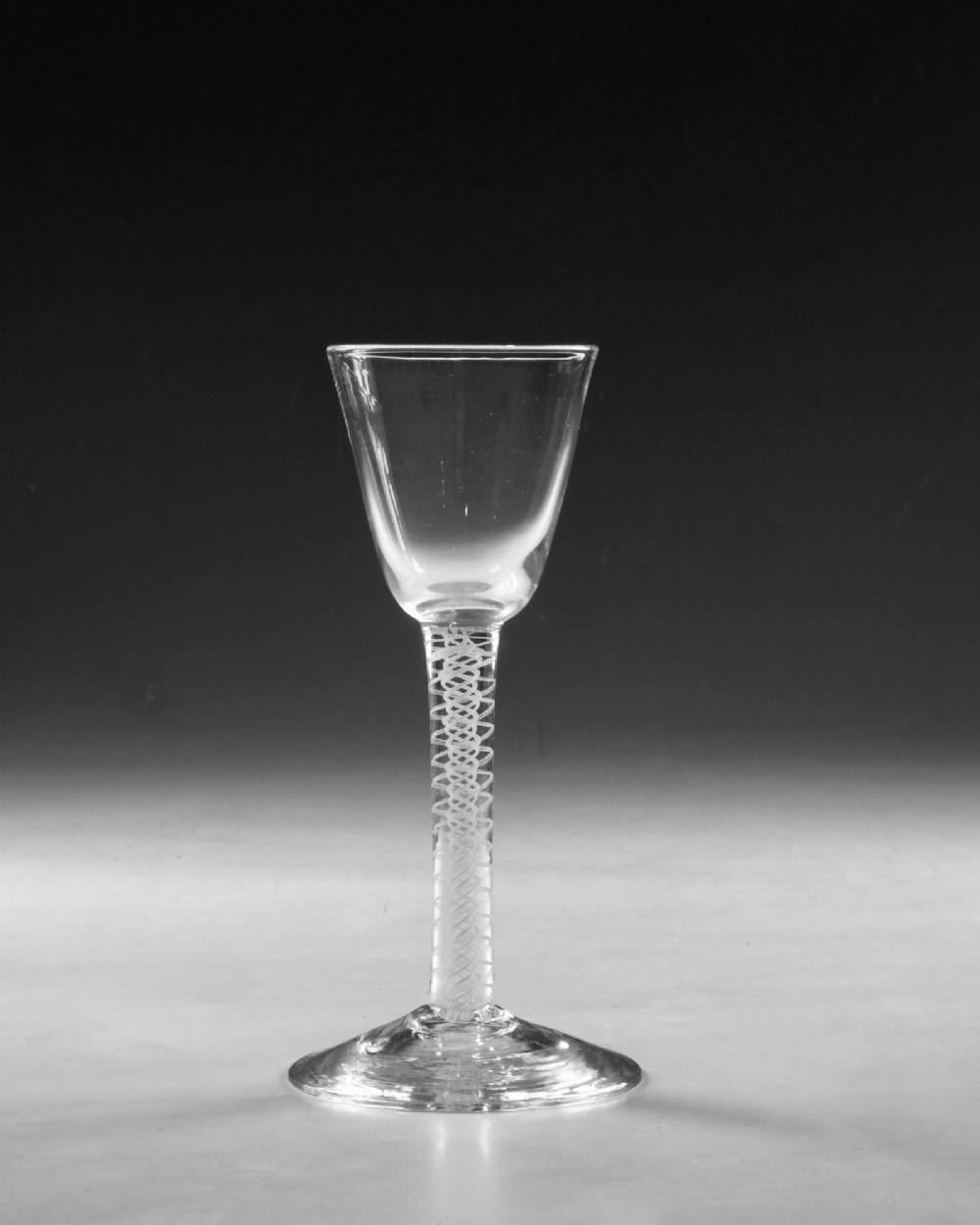 A Georgian clear lead crystal wine glass featuring a bell-shaped bowl, a stem with an internal white opaque twist pattern, and a conical foot. View II