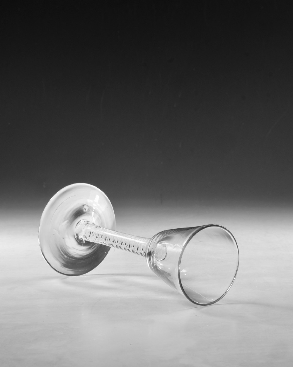 A Georgian clear lead crystal wine glass featuring a bell-shaped bowl, a stem with an internal white opaque twist pattern, and a conical foot. View IV
