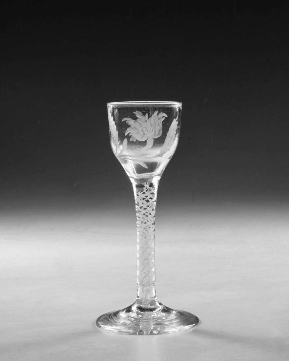 An 18th-century Georgian clear glass wine goblet featuring a wheel-engraved floral bowl, an internal opaque white twist stem, and a flat conical base. View II