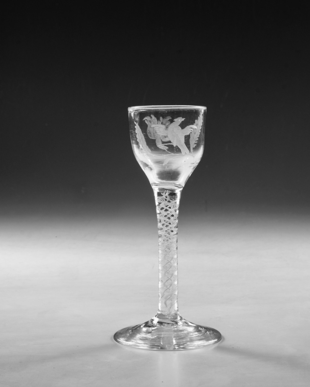 An 18th-century Georgian clear glass wine goblet featuring a wheel-engraved floral bowl, an internal opaque white twist stem, and a flat conical base. View III