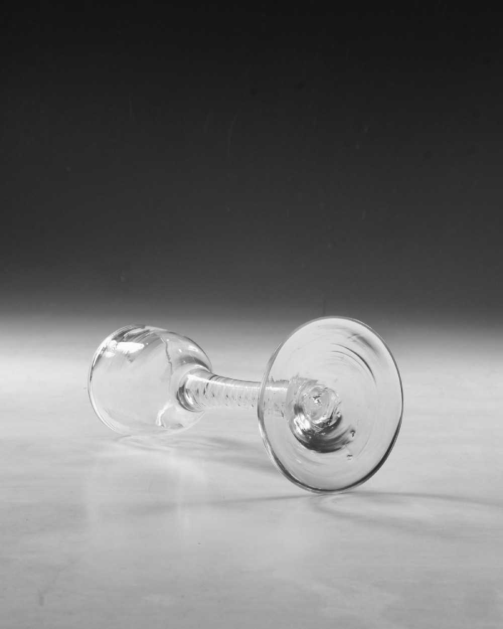 An 18th-century Georgian clear glass wine goblet featuring a wheel-engraved floral bowl, an internal opaque white twist stem, and a flat conical base. View IV