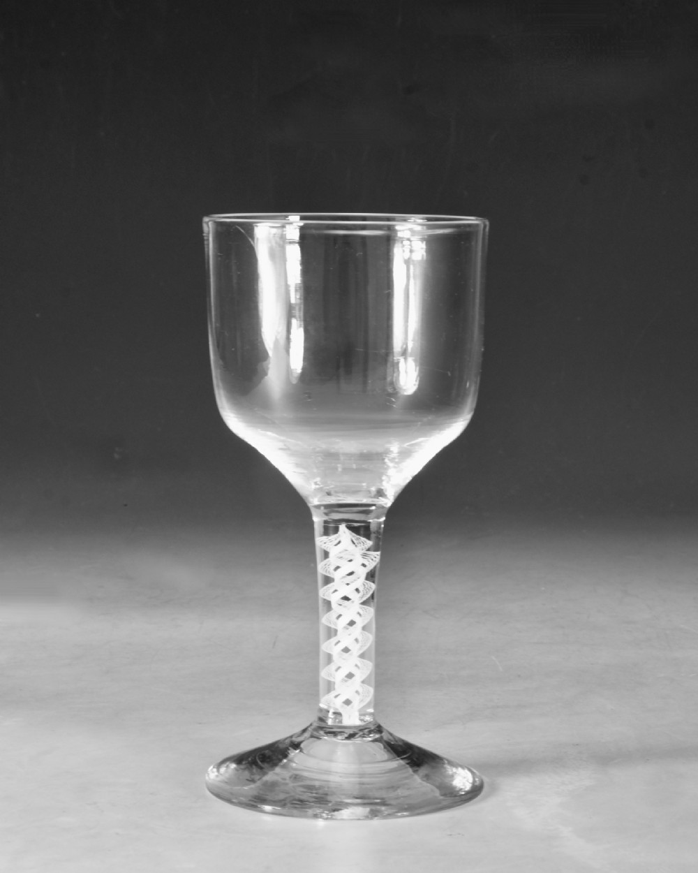 An 18th-century clear glass wine goblet featuring a round bowl supported by an opaque white spiral twist stem on a conical foot. View II
