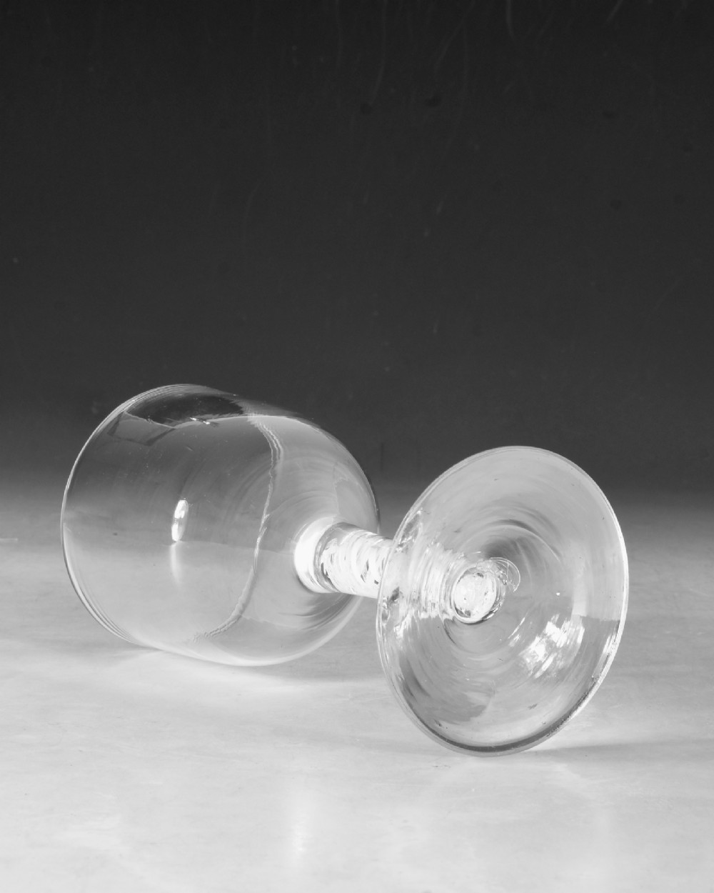 An 18th-century clear glass wine goblet featuring a round bowl supported by an opaque white spiral twist stem on a conical foot. View III